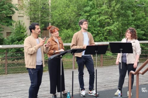 4 chanteurs devant une rivière aux abords boisés