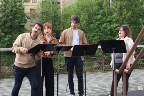 4 chanteurs derrière des pupitres devant des arbres
