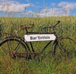 panneau sur un vélo au bord d'un champ indiquant l'accès au festival