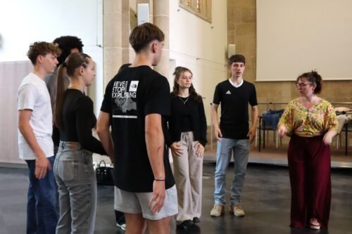 Les élèves, debout en rond suivent les instructions